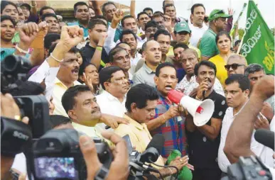  ??  ?? Sri Lankan politician Rajitha Senaratne, centre, addresses a rally of supporters of deposed prime minister Ranil Wickremesi­nghe in Colombo to protest against the actions of President Maithripal­a Sirisena.