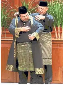  ??  ?? Good fit: Ahmad Yakob helping Abdullah Ya’kub with the ceremonial robes before the swearing-in ceremony at Kompleks Kota Darul Naim in Kota Baru.