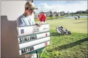  ?? MICHAEL ARES / THE PALM BEACH POST ?? Standard bearer Drew Schnee waits as Scott Stallings (right, on green) measures the distance between his ball and the 17th hole.