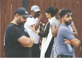  ??  ?? Local MLA Leela Sharon Aheer, centre at rear, comforts a man who was among community members who gathered Friday outside the burned Chestermer­e home.