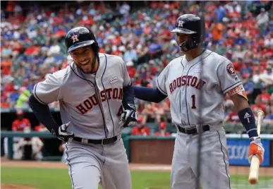  ?? Associated Press ?? Houston Astros' George Springer (4) and Carlos Correa (1) celebrate Springer's solo home run that came off a pitch from Texas Rangers' Martin Perez in the first inning of a baseball game Sunday in Arlington, Texas.