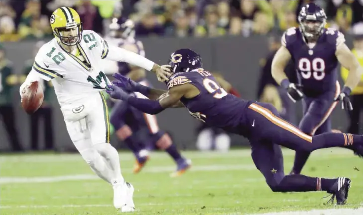  ??  ?? GREEN BAY: Green Bay Packers quarterbac­k Aaron Rodgers (12) tries to run away from Chicago Bears outside linebacker Leonard Floyd (94) during the first half of an NFL football game, Thursday, in Green Bay, Wis. — AP