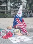  ?? BLOOMBERG ?? A protester wearing American flag-themed clothing sits on a sidewalk.