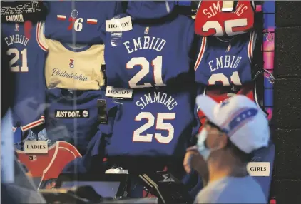  ?? AP PHOTO/MATT SLOCUM ?? A fan shops for souvenirs, on Thursday in Philadelph­ia. U.S. consumer confidence rose in October after three straight declines as the public’s anxiety about the delta variant of coronaviru­s appear to have abated.