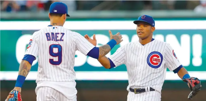  ?? AP ?? Addison Russell ( right), who hit a grand slam in the fifth inning for his second homer in two days, and Javy Baez celebrate after beating the Twins on Friday atWrigley Field. The game- time temperatur­e was 96 degrees.