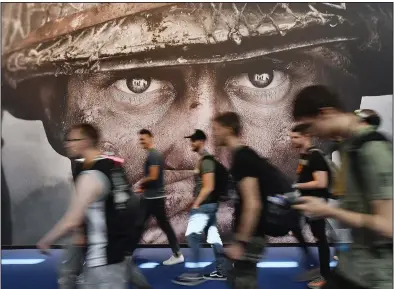  ?? (AP/Martin Meissner) ?? Visitors pass an advertisem­ent for a Call of Duty video game at the Gamescom fair in Cologne, Germany, in 2017.