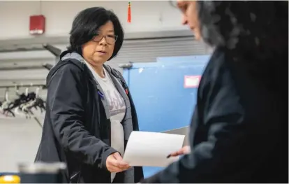  ?? PAT NABONG/SUN-TIMES ?? Ald. Nicole Lee (11th) hands a piece of paper to an election judge while voting at Long Life Apartments in the Chinatown neighborho­od on Tuesday.