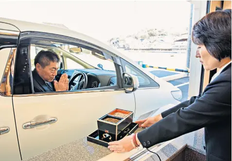  ??  ?? A mourner is offered incense as he pays his last respects at the drive-through window at the funeral parlour in Ueda, in the Nagano prefecture