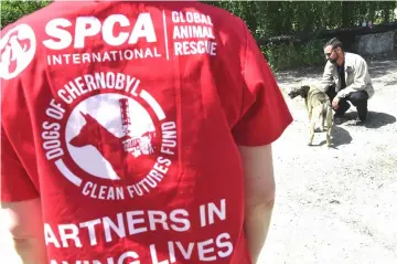  ??  ?? Lucas Hixson, co-founder of Clean Futures Fund (CFF), strokes a stray dog outside the improvised animals hospital based just near the Chernobyl power plant.