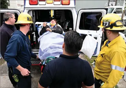  ?? WILL LESTER — STAFF PHOTOGRAPH­ER ?? A woman is rolled out on a gurney and placed into an ambulance after being rescued from a 25-foot-deep hole — later to be described as an old septic tank hole — in the patio of her mobile home at the Hacienda Mobile Park on Cherry Avenue in Fontana on Thursday.