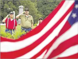  ?? DEBORAH CANNON / AMERICAN-STATESMAN 2014 ?? Edward Harris (from left), James Stuart and Stuart’s daughter, Abigail, 8, salute as the flag is raised during the American Legion Memorial Day program at San Marcos Cemetery last year. Harris and Stuart are Army veterans.