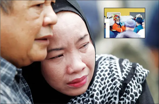  ?? (AP) ?? Family members cry outside an Islamic religious school following a fire on the outskirts of Kuala Lumpur on Sept 14. (Inset): The body of a victim is carried out by rescue personnel from an Islamic religious school after the
fire.