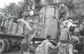  ?? (AP PHOTO/MOISES CASTILLO) ?? The group of some 2,000 Honduran migrants hit the road in Guatemala again Wednesday, hoping to reach the United States despite President Donald Trump's threat to cut off aid to Central American countries that don't stop them.