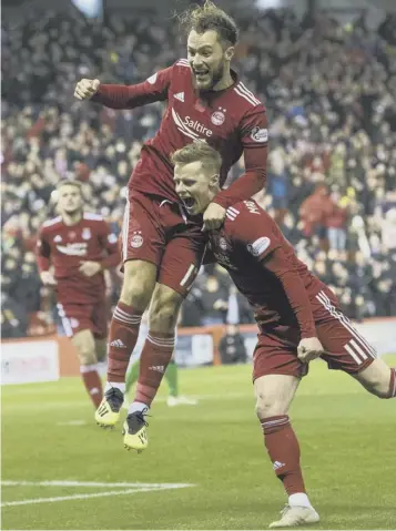  ??  ?? Aberdeen’s Stevie May leaps on goalscorer Gary Mackay-steven at a blustery Pittodrie last night.