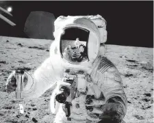  ??  ?? Apollo 12 astronaut Alan L. Bean holds a special environmen­tal sample container which holds soil collected during a moonwalk. Commander Charles “Pete” Conrad had just put a soil sample in the tube with a shovel. Conrad took the photograph and can be seen in the reflection in Bean’s visor.