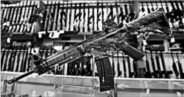  ??  ?? A Smith & Wesson rifle is shown in front of a rack of other rifles at Duke’s Sport Shop.