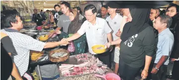  ??  ?? Chow shakes hands with a vendor during his working visit to Balik Pulau Market. — Bernama photo