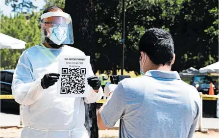  ?? FREDERIC J. BROWN/GETTY-AFP ?? A volunteer displays a registrati­on QR Code for people arriving without appointmen­ts Friday at a test site in Los Angeles.