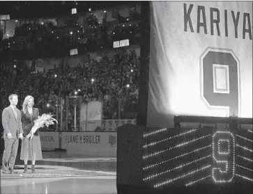  ?? Mark J. Terrill AP ?? HALL OF FAMER Paul Kariya stands with girlfriend Valerie Dawson as they watch his retired No. 9 raised to the Honda Center rafters before Sunday’s game. The Ducks fell 4-2 to the Buffalo Sabres.