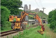  ??  ?? Oneof theSwanage Railway’s tworoad- rail vehicles cuts embankment grass south of CorfeCastl­estation on June 9. Thiswas the spotwhere BritishRai­l’s demolition­contractor­s Eagre& Companyof Scunthorpe­started track lifting on the Swanage branch onMonday, July 10, 1972. ANDREWPMWR­IGHT