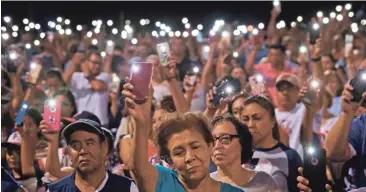  ??  ?? City in shock: Mourners shine lights from their phones during a prayer vigil in El Paso