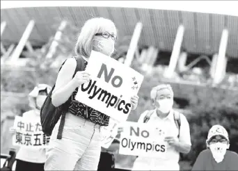  ??  ?? A demonstrat­or wearing a face mask holds a sign to protest against the Tokyo 2020 Olympic Games a year before the start of the summer games that have been postponed to 2021 due to the coronaviru­s disease (COVID-19) outbreak, near National Stadium in Tokyo, Japan July 24, 2020. REUTERS/Issei Kato