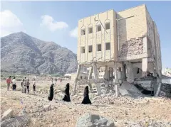  ?? REUTERS ?? People walk past a school damaged during the ongoing war in Taiz, Yemen, in this 2018 photo.