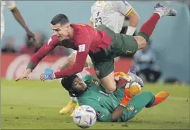  ?? Darko Bandic Associated Press ?? CRISTIANO RONALDO of Portugal falls over Ghana goalkeeper Lawrence AtiZigi in the teams’ opening match. Ronaldo scored on a penalty kick in a 3-2 win.