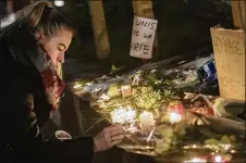  ?? THOMAS LOHNES / GETTY IMAGES ?? A woman lights a candle at the Christmas market where the day before a man shot 14 people, killing at least two, in Strasbourg, France.