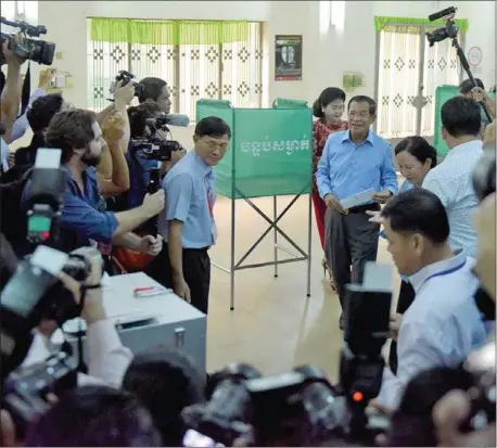  ?? CHHIN SOTHY/AFP TANG ?? Cambodia’s Prime Minister and leader of the ruling Cambodian People’s Party (CPP) Hun Sen (centre) and his wife Bun Rany (behind) prepare to cast their votes during the general elections at a polling station in Kandal province, outside of Phnom Penh,...