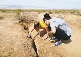  ?? Mario Tama Getty Images ?? RIDGECREST residents inspect a fissure after two large temblors struck in July, destabiliz­ing the remote region between the Sierra Nevada and Death Valley.