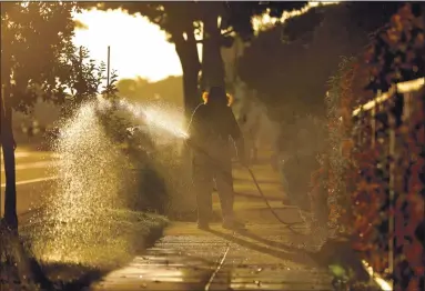  ?? PHOTOS BY RAY CHAVEZ — STAFF PHOTOGRAPH­ER ?? A man waters a lawn and hoses down a sidewalk in Alameda on May 4. Such an activity was banned in the previous drought.