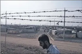  ?? AP/MARKO DROBNJAKOV­IC ?? A man walks Tuesday inside the Baharka camp for displaced Iraqis on the outskirts of Irbil, Iraq.