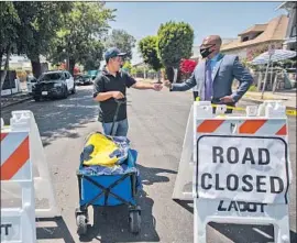  ?? Francine Orr Los Angeles Times ?? JAMES WESTBROOKS, right, aide to Councilman Curren Price, speaks with resident Mario Delgado near the corner of East 27th Street and Stanford Avenue.