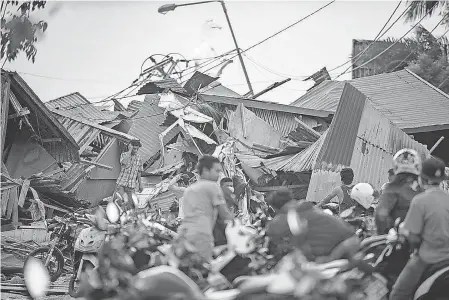  ?? BAY ISMOYO/GETTY IMAGES ?? Residents search for their belongings in Palu in central Sulawesi, Indonesia, on Saturday.