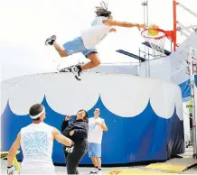  ?? BRENDAN MILLER ?? Jerry Burrell, founder and owner of Acrodunk, soars over a volunteer during a show on the grounds at the Stampede. The group first performed at the Grandstand Show in 2010.