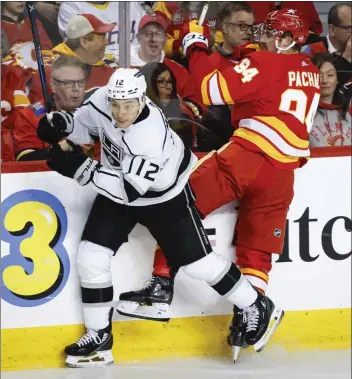  ?? PHOTOS BY JEFF MCINTOSH — THE CANADIAN PRESS VIA AP ?? The Kings' Trevor Moore, left, checks the Flames' Brayden Pachal along the boards during Tuesday's game at Calgary.