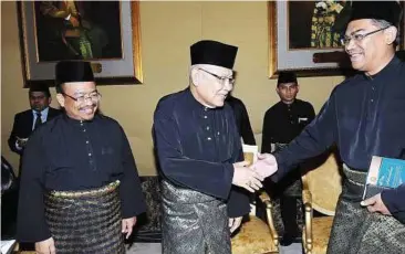  ??  ?? New beginning: Azizan (centre) shaking hands with Dr Ismail after the swearing-in ceremony at Balai Penghadapa­n Istana Anak Bukit in Alor Setar yesterday. Looking on is Phahrolraz­i (left).