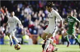  ?? — AFP ?? MADRID: Real Madrid’s Welsh forward Gareth Bale (L) scores past Leganes’s goalkeeper Serantes during the Spanish league football match Real Madrid CF vs Club Deportivo Leganes SAD at the Santiago Bernabeu stadium in Madrid yesterday.