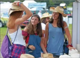  ?? PETE BANNAN – DIGITAL FIRST MEDIA ?? Jill Arrowsmith of Downingtow­n, with friends Grace Hollis and Grace Poluch of Chester Springs, look for the perfect cowboy hat at the Citadel Country Spirit USA Festival at Ludwig’s Corner show grounds Saturday.