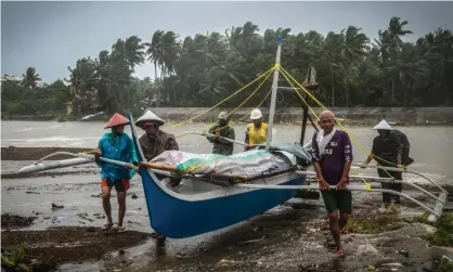  ??  ?? Fishermen carry a boat to higher ground in Baybay, eastern Samar, Philippine­s, during Typhoon Phanfone. Photograph: Alren Beronio/ AFP via Getty Images