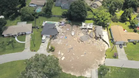  ??  ?? This aerial photo taken Friday shows debris after a sinkhole swallowed a boat and destroyed two homes in Land O’Lakes, Florida.
