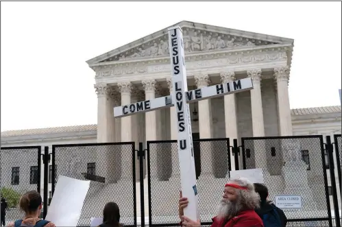  ?? (AP/Jose Luis Magana) ?? A demonstrat­or holding a cross
protests Thursday outside of the U.S. Supreme Court in Washington.