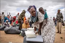  ?? ?? A woman who have been displaced from her home due to heavy floods carry her baby on the back while getting some items delivered by UNICEF and Kenya Red Cross at a camp for displaced people in Garissa.