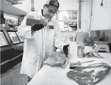  ?? Bob Owen / Staff photograph­er ?? Joe Doria, manager at Bolner’s Meat Market in San Antonio, applies seasoning as a dry rub to a brisket. He said that this year’s brisket high season started early — before Memorial Day — and is going strong.