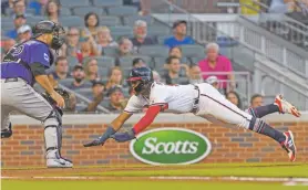  ?? DANNY KARNIK/ASSOCIATED PRESS ?? The Braves’ Ronald Acuna Jr. dives toward home plate to score on a sacrifice fly ball as Rockies catcher Chris Iannetta waits for the ball Friday in Atlanta. The Rockies won, 11-5.