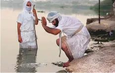  ?? AP ?? Followers of the ancient Mandaean religious sect perform their rituals along a strip of embankment on the Tigris River reserved for them, in Baghdad on October 14.