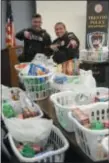  ??  ?? Trenton police officers Steven Garzio, left, and Walter DeLeon, right, hand out baskets of groceries to Trenton families during the department’s annual Thanksgivi­ng meal giveaway.