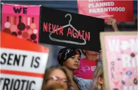  ?? Charlie Neibergall/Associated Press file photo ?? ■ August Mulvihill, of Norwalk, Iowa, center, holds a sign during a rally May 21 to protest recent abortion bans at the Statehouse in Des Moines, Iowa.