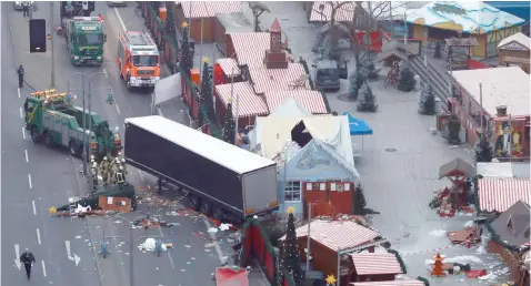  ?? — AFP ?? A truck is towed away as forensic experts examine the scene around a truck that crashed into a Christmas market in Berlin.